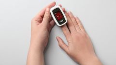 This image shows a woman using a fingertip pulse oximeter.